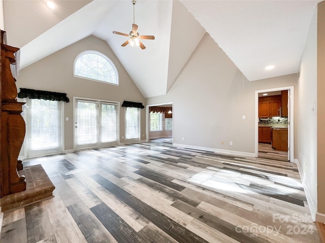 unfurnished living room with light hardwood / wood-style flooring, high vaulted ceiling, and ceiling fan