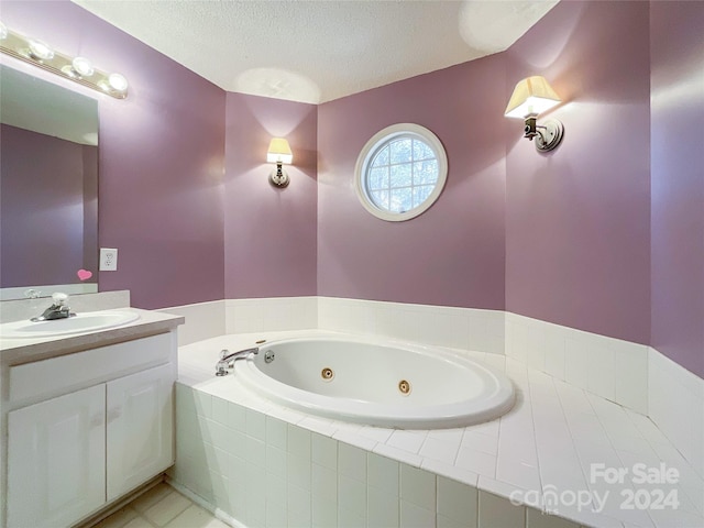 bathroom featuring vanity, a textured ceiling, and tiled tub