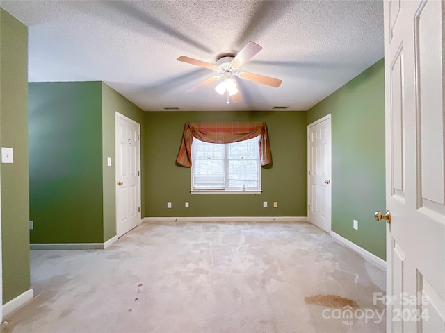 carpeted spare room with a textured ceiling and ceiling fan