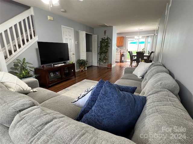 living room with a textured ceiling, dark wood-type flooring, and ceiling fan