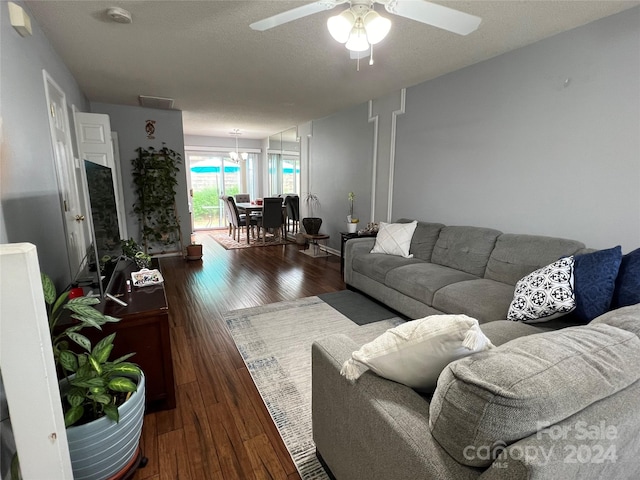 living room with a textured ceiling, ceiling fan, and dark hardwood / wood-style flooring