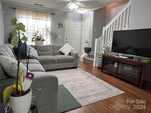 living room featuring ceiling fan, a textured ceiling, and hardwood / wood-style floors