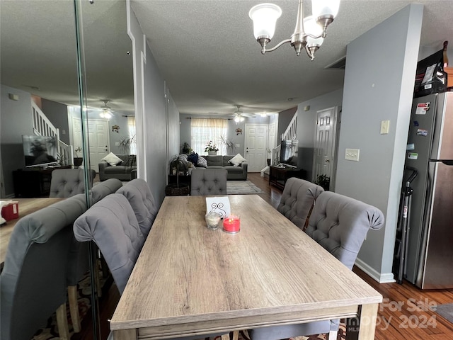 dining area with a textured ceiling, hardwood / wood-style flooring, and ceiling fan with notable chandelier