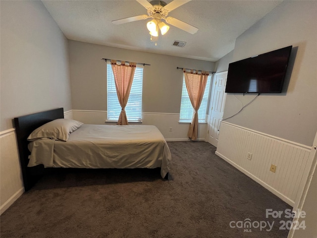 carpeted bedroom with a textured ceiling, vaulted ceiling, and ceiling fan