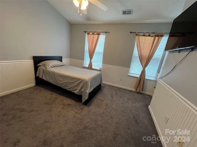 bedroom with dark colored carpet, a textured ceiling, and ceiling fan