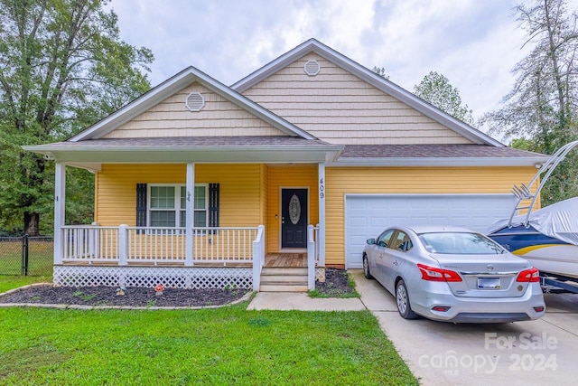 view of front of property with a front lawn, covered porch, and a garage