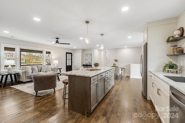 kitchen with white cabinets, dark hardwood / wood-style floors, stainless steel appliances, and decorative light fixtures