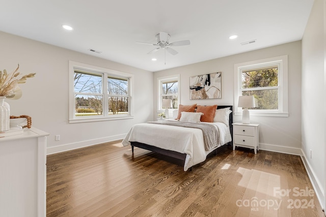 bedroom featuring ceiling fan, dark wood-type flooring, and multiple windows