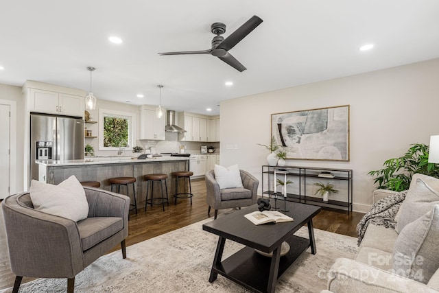 living room with ceiling fan, light wood-type flooring, and sink