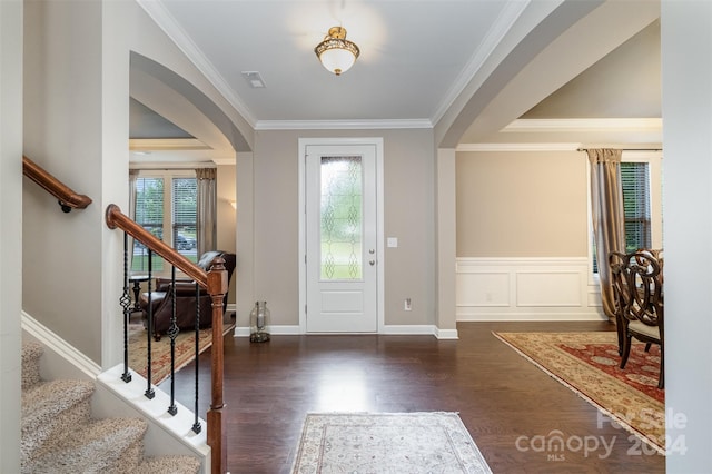 foyer entrance with dark wood-type flooring, a wealth of natural light, and ornamental molding