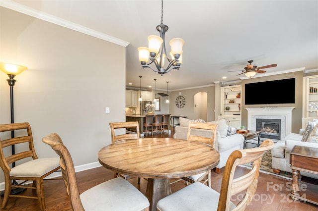 dining space featuring ornamental molding, ceiling fan with notable chandelier, dark hardwood / wood-style flooring, and built in features