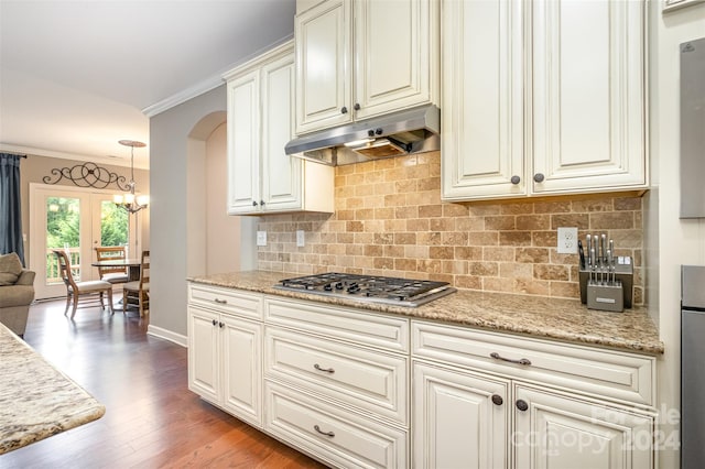 kitchen with stainless steel gas cooktop, ornamental molding, tasteful backsplash, wood-type flooring, and pendant lighting