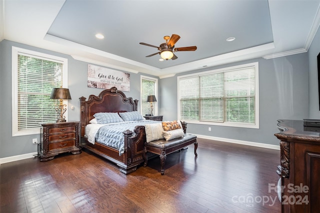 bedroom with dark wood-type flooring, ornamental molding, a tray ceiling, and ceiling fan