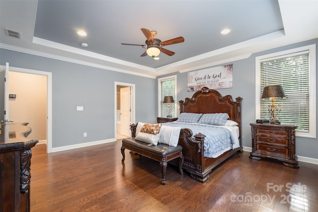 bedroom featuring dark hardwood / wood-style flooring, a tray ceiling, multiple windows, and ceiling fan