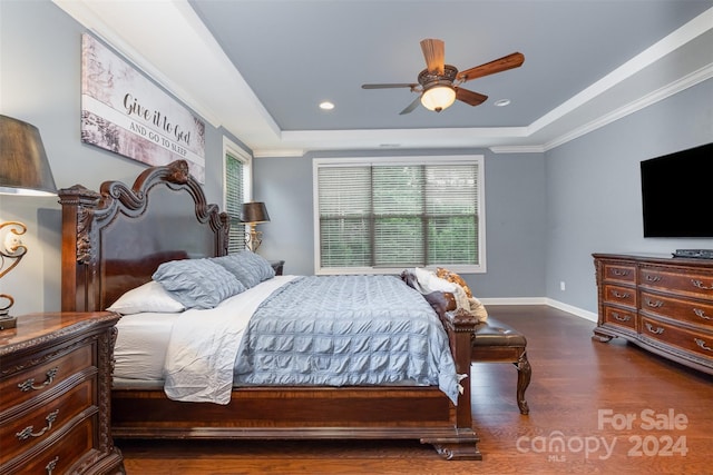 bedroom with dark hardwood / wood-style flooring, ceiling fan, crown molding, and a tray ceiling