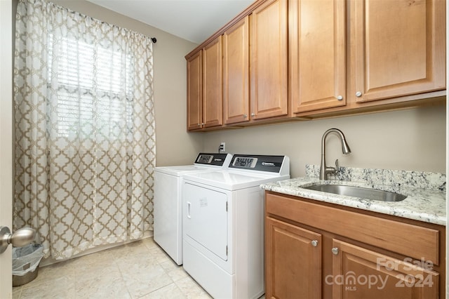 clothes washing area featuring cabinets, light tile patterned flooring, sink, and washing machine and clothes dryer