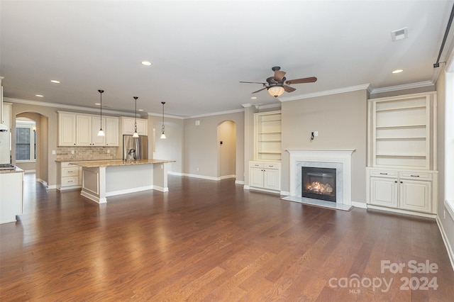 unfurnished living room featuring built in shelves, dark hardwood / wood-style flooring, and ornamental molding