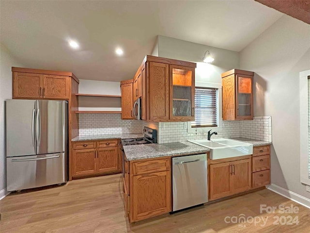 kitchen featuring lofted ceiling, decorative backsplash, sink, light wood-type flooring, and appliances with stainless steel finishes