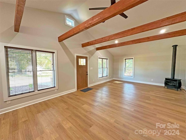 unfurnished living room with light hardwood / wood-style flooring, lofted ceiling with beams, and a wood stove