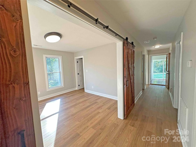 corridor featuring light hardwood / wood-style floors and a barn door