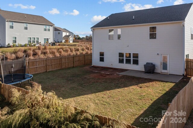 back of house with a patio, a trampoline, and a yard