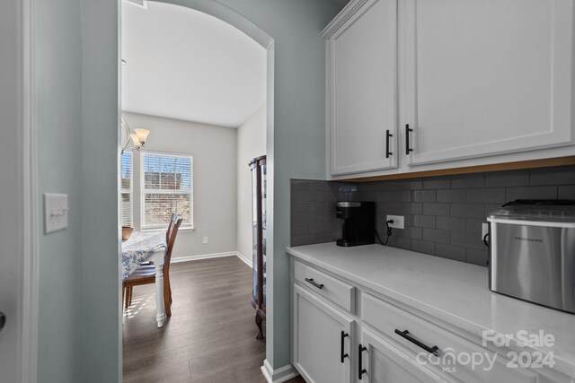 kitchen with dark wood-type flooring, white cabinets, and tasteful backsplash