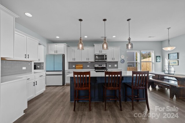 kitchen featuring appliances with stainless steel finishes, white cabinetry, dark hardwood / wood-style floors, and pendant lighting