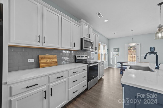 kitchen with sink, hanging light fixtures, white cabinetry, stainless steel appliances, and dark hardwood / wood-style floors