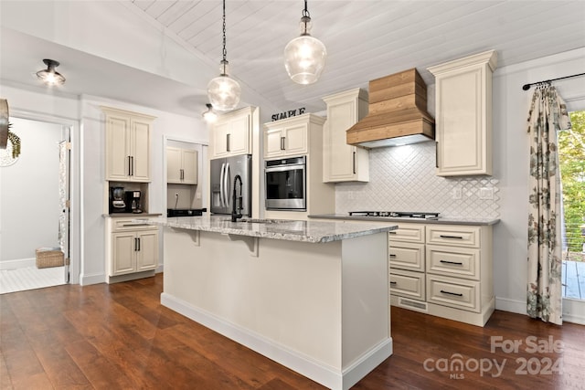 kitchen featuring appliances with stainless steel finishes, custom exhaust hood, a wealth of natural light, and cream cabinetry