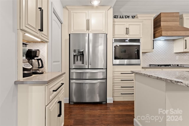 kitchen with dark hardwood / wood-style flooring, light stone countertops, stainless steel appliances, and cream cabinetry