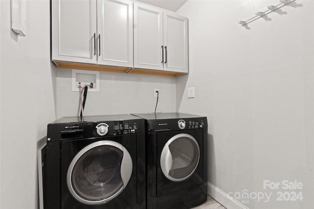 clothes washing area featuring light tile patterned floors, cabinets, and washing machine and clothes dryer