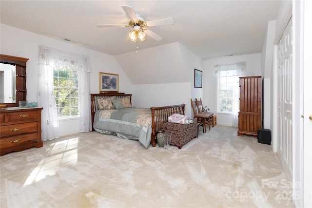 bedroom with ceiling fan, light colored carpet, a closet, and lofted ceiling