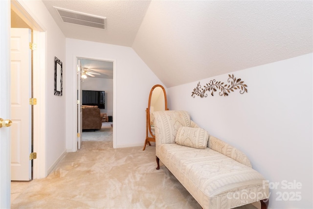 living area featuring a textured ceiling, light colored carpet, lofted ceiling, and ceiling fan