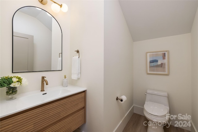 bathroom with vanity, wood-type flooring, vaulted ceiling, and toilet