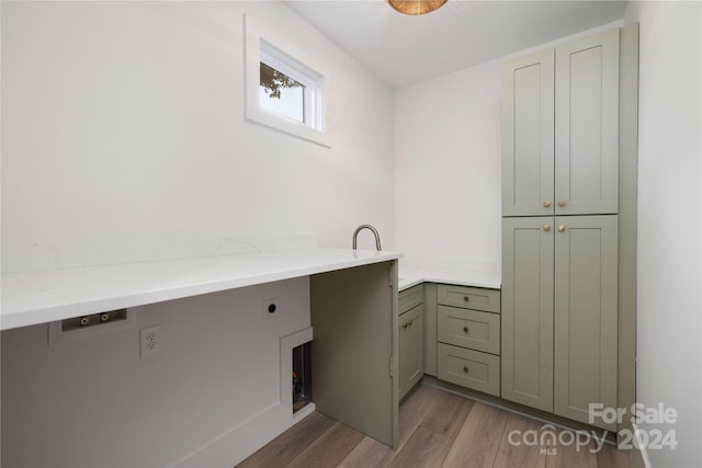 washroom with electric dryer hookup, light hardwood / wood-style floors, and cabinets