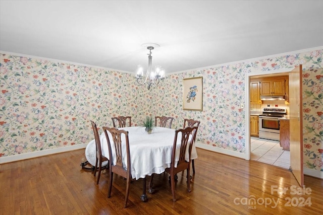 dining area featuring light hardwood / wood-style floors, crown molding, and a notable chandelier