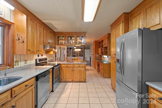 kitchen with sink, light tile patterned flooring, kitchen peninsula, stainless steel appliances, and a chandelier