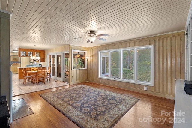 living room featuring light hardwood / wood-style flooring, wooden walls, and wooden ceiling