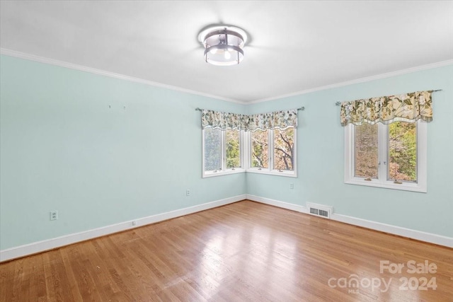 empty room with hardwood / wood-style floors and crown molding