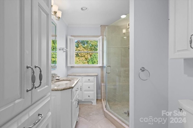 bathroom featuring toilet, ornamental molding, a shower with shower door, vanity, and tile patterned flooring