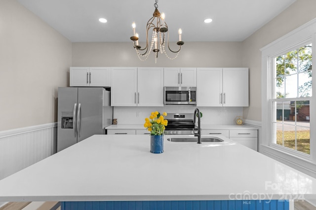 kitchen with white cabinetry, a kitchen island with sink, stainless steel appliances, and sink