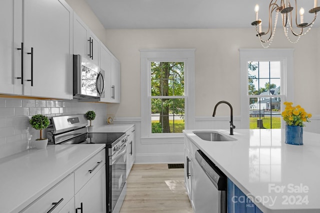 kitchen featuring sink, white cabinetry, stainless steel appliances, and plenty of natural light