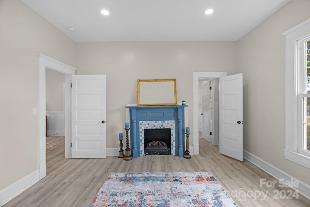 unfurnished living room with a tiled fireplace and light wood-type flooring