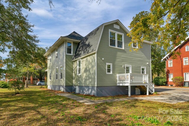 rear view of property featuring a yard and a deck