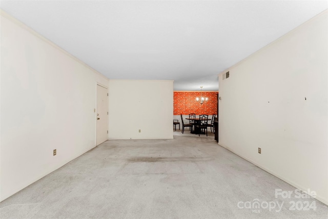 carpeted empty room featuring an inviting chandelier