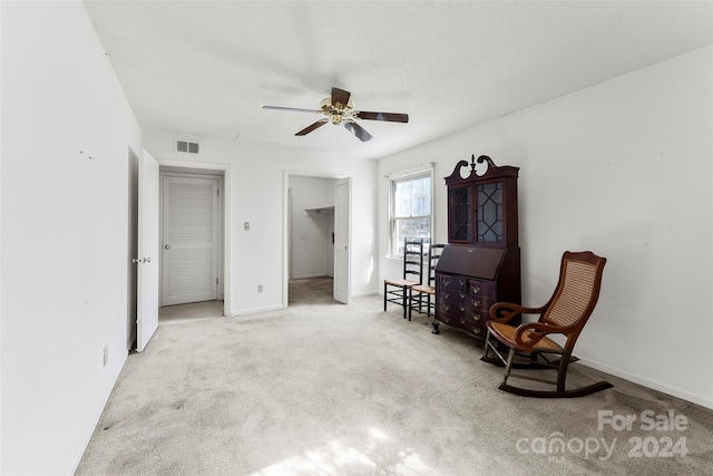 sitting room with ceiling fan and light carpet