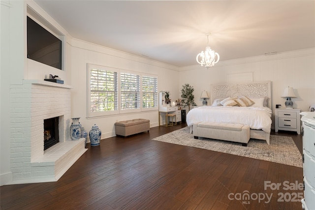 bedroom with an inviting chandelier, a brick fireplace, and dark hardwood / wood-style flooring