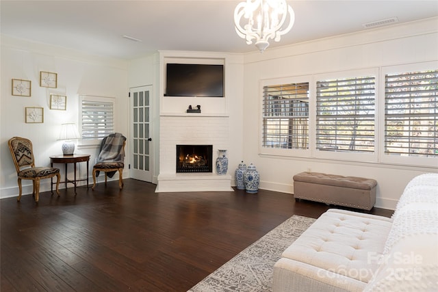 living room featuring dark hardwood / wood-style flooring, a fireplace, a notable chandelier, and plenty of natural light