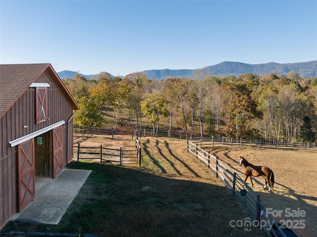 view of yard with a rural view, a mountain view, and an outbuilding