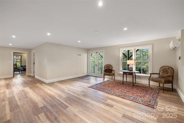 living area featuring light wood-type flooring and a wall unit AC